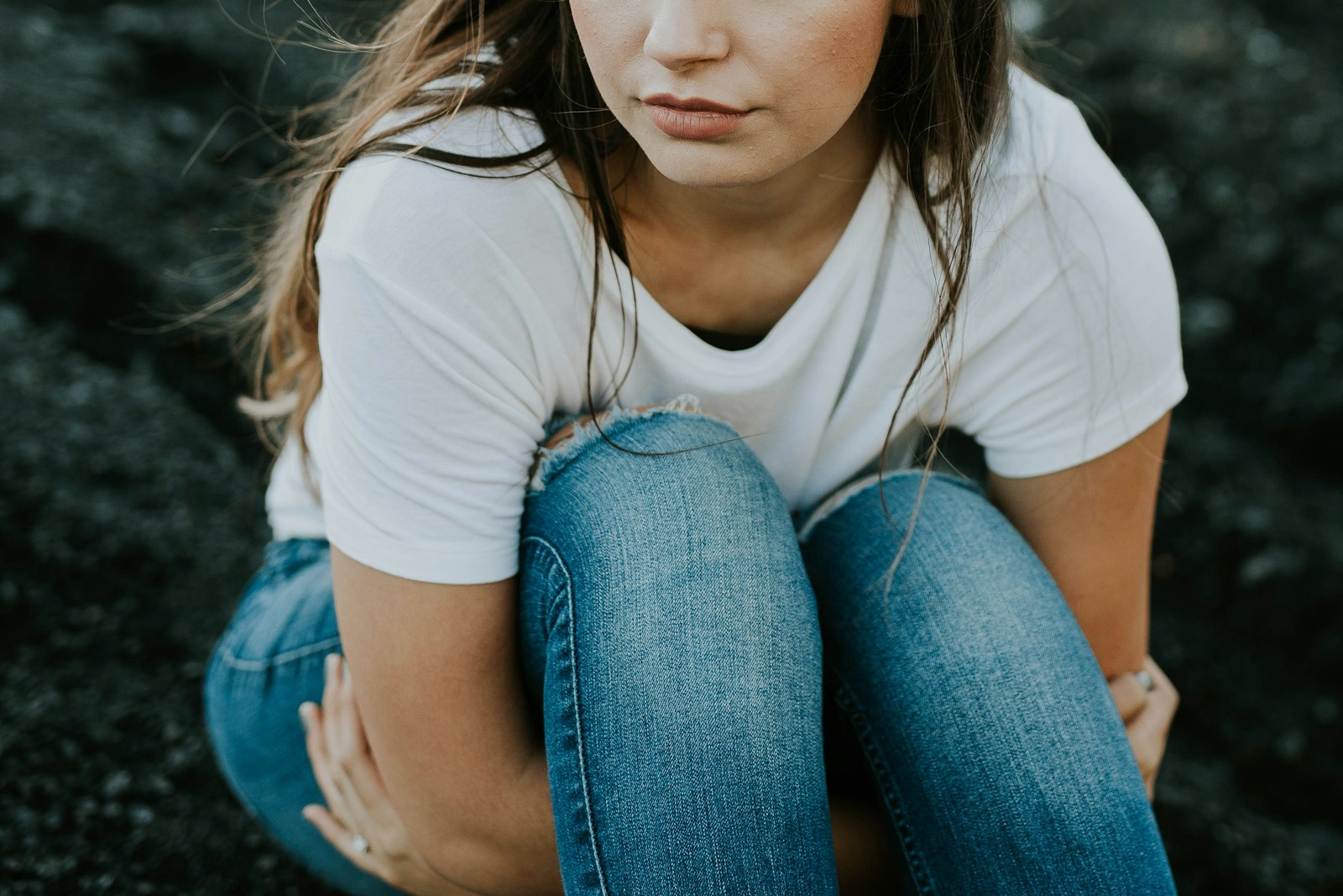 Behavioral health services. A woman crouching looking into the distance.